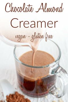 chocolate almond creamer is being poured into a glass mug filled with cocoa and other ingredients