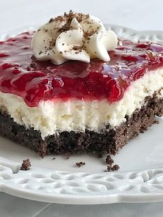 a piece of cake with whipped cream and cherries on top sits on a white plate