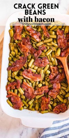 bacon and green beans in a white casserole dish with a wooden spoon on the side