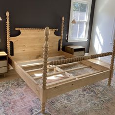 a wooden bed frame sitting on top of a rug in a bedroom next to a window