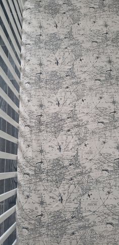 a white and black patterned curtain next to a window with blind blinds on top of it