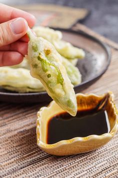 a person dipping sauce onto some food on a plate