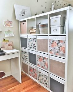 a white desk with lots of drawers and baskets on it's sides in front of a wall