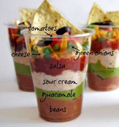 three cups filled with different types of food and chips on top of each cup are labeled