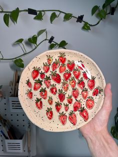 a hand holding a plate with strawberries on it