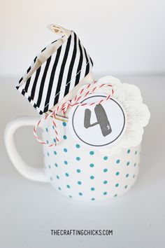 a coffee cup with a black and white striped hat on it, next to a tag that says the crafting chicks