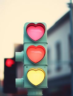 a traffic light with two hearts painted on it's red, yellow and green lights