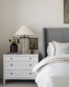 a white bed sitting next to a night stand with two lamps on top of it