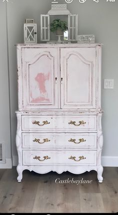 an old dresser is painted white with gold trim