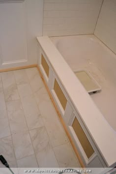 a bath tub sitting inside of a bathroom next to a tiled floor and white walls