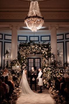 the bride and groom are getting married in front of an elegant chandelier at their wedding ceremony