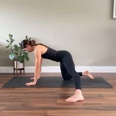 a woman is doing yoga on a mat in front of a potted plant and chair