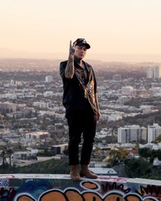 a man standing on top of a graffiti covered wall with his hand in the air