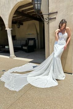 a woman in a wedding dress leaning against a wall