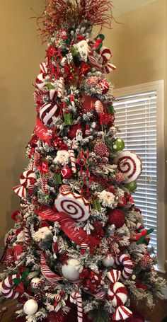 a christmas tree decorated with candy canes, ornaments and ribbons in red and white