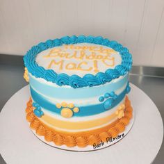 a birthday cake with blue, yellow and orange frosting on it's side