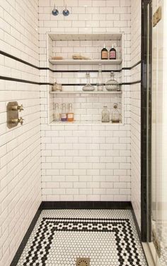 a white tiled shower with black and white floor tiles on the walls, shelves above it