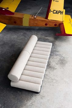 a white couch sitting on top of a cement floor next to a yellow and red plane