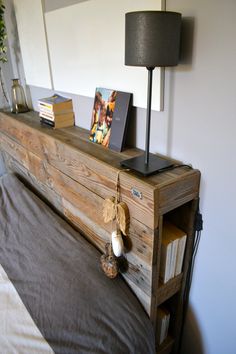 a bed with a wooden head board and books on it, next to a lamp