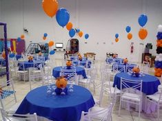 a room filled with tables and chairs covered in blue tablecloths, orange and white balloons