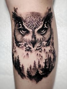 an owl tattoo on the leg with trees and mountains in the background, is shown