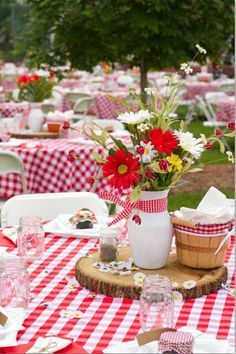 a red and white checkered table cloth with flowers in a vase on it,