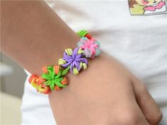 a woman wearing a colorful bracelet with flowers on it's wrist and an open book in the background