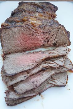 sliced meat sitting on top of a white cutting board