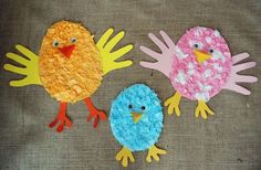 three paper plate birds sitting next to each other on top of a cloth covered surface