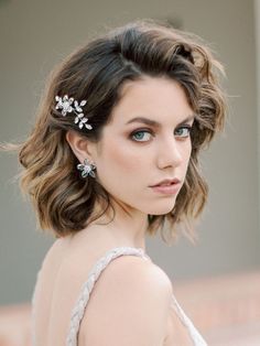 a close up of a woman with short hair wearing a white dress and silver earrings