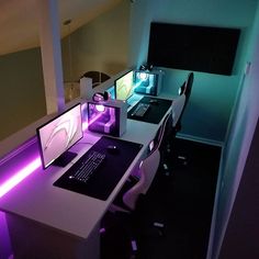 there is a desk with a computer on it and purple lights in the room behind it