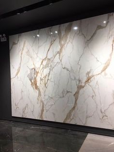 a large white marble wall in a room with black walls and flooring on the side