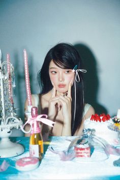 a woman sitting in front of a table with cake and candles on top of it