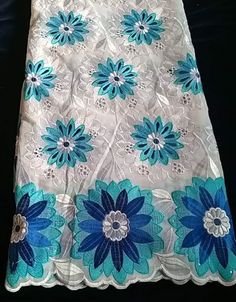 a white and blue flowered lace with flowers on it's side, sitting on a black surface