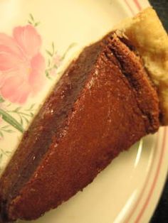 a piece of chocolate pie sitting on top of a white and pink flowered plate