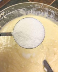 a mixing bowl filled with yellow batter and a scoop full of sugar on the side