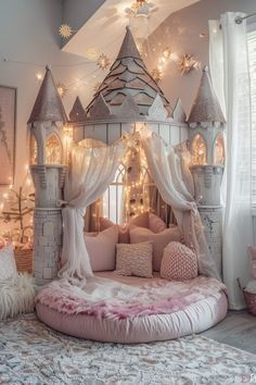 a princess castle bed with fairy lights on the ceiling and pink pillows in front of it