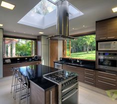 a modern kitchen with an island and stainless steel stove top oven in front of large windows