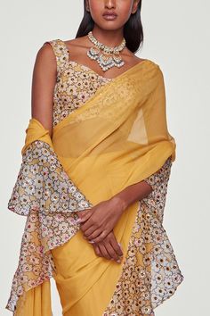 Yellow saree with floral print and embellished ruffle borders. Paired with embellished, printed sleeveless blouse.
Component: 2
Pattern: Embroidered,Printed
Type Of Work: Floral
Neckline: Sweetheart
Sleeve Type: Sleeveless
Fabric: Georgette, Organza
Color: Yellow
Other Details: 
Ruffle border
Metallic embellishments
Embellished blouse
Occasion: Reception,Destination Wedding  - Aza Fashions Aisha Rao, Ruffle Saree, Yellow Saree, Printed Sleeveless Blouse, Embellished Blouse, Blouse For Women, Saree With Blouse, Blouse Online, Festival Wear