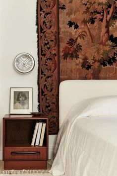 a bedroom with a bed, nightstand and tapestry on the wall