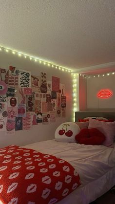 a bedroom decorated in red and white with pictures on the wall above the bed, along with lights