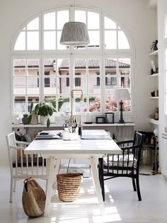 a white table and chairs in front of an arched window with potted plants on it