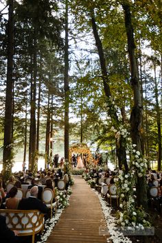 an outdoor ceremony in the woods with white flowers and greenery on either side of the aisle