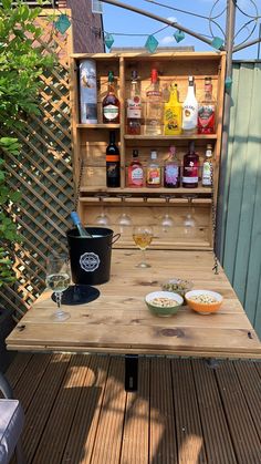 an outdoor table with drinks and bowls on it