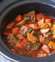 a crock pot filled with stew and carrots