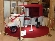 a white and red golf cart on display in a room with lights around the perimeter