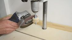 a person using a grinder on a piece of wood with a machine in the background