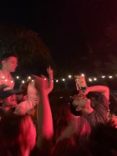 a group of people standing around each other at a concert with their cell phones up in the air