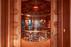 an open door leading to a library with bookshelves in the center and stairs on either side