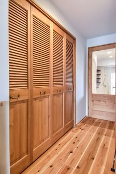 an empty room with wooden closets and hard wood flooring on one side, large sliding doors in the other